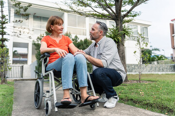 Fototapeta na wymiar Caucasian senior woman support husband on wheelchair outdoor in garden.