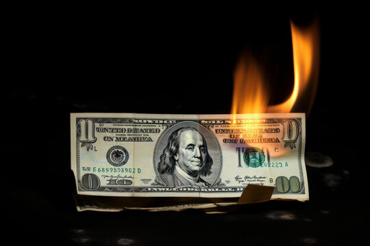 Isolated burning dollar bill on a black background, a powerful image of financial crisis and loss, warning against the dangers of materialism. AI Generated