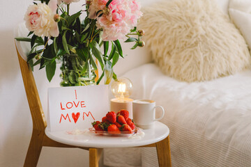 Breakfast for Mothers Day. Heart shaped white plate with fresh strawberries, cup of coffee, gift...