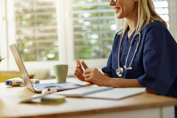 Close up of female doctor doing some paperwork and using laptop while working at doctor's office