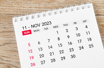 The November 2023 desk calendar for 2023 on wooden background.