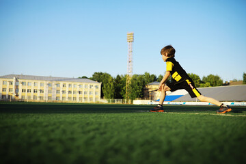 The child goes in for sports at the stadium. The boy is training before playing football.