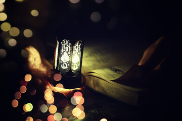 Ramadan Kareem background. Ornamental Arabic lantern glowing and the holy book of Quran.