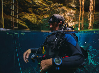 underwater split shot of a cave diver in a cenote