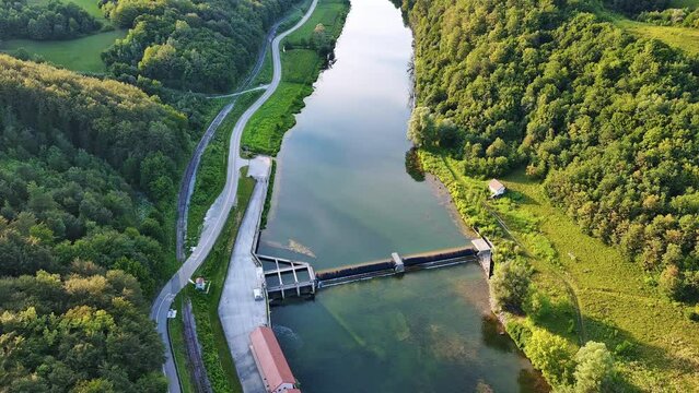 The Kupa river with a hydroelectric power plant near the road in a dense green forest