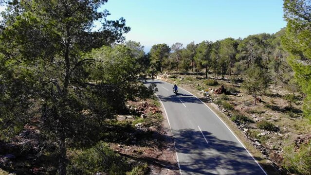 Mc passing by on a road in the nature on Ibiza, filmed with drone.