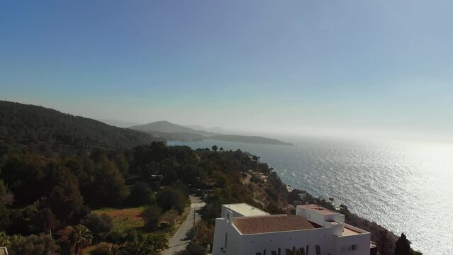 Drone rising by a building by the coast on Ibiza.