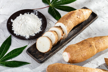 pile of cassava root and cassava flour on a gray and white textured background (Manihot esculenta)