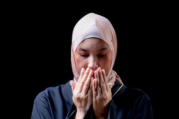 The image of an Asian Muslim woman in the Islamic religion in hijab in cream and black color. She was praying in a beautiful mosque out of respect for God.