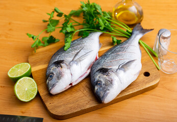 Raw dorado fish served with sprig of greens and juicy lime