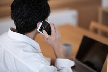 仕事の電話をする日本人男性の後ろ姿