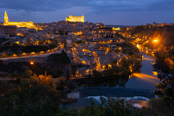 Fototapeta na wymiar Cityscape of illuminated Toledo in evening with view of Alcazar and Tagus River. Castilla-La Mancha, Spain.
