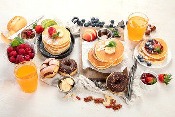 Pancakes with fresh fruits, donuts and coffee on a white background.