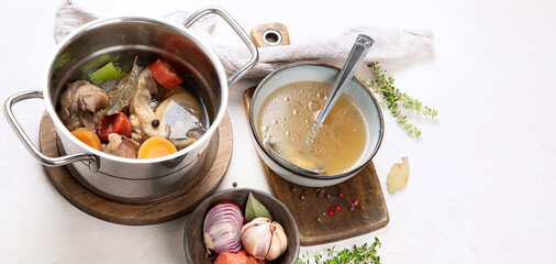 Pot of soup with beef and fresh vegetables on a white background.