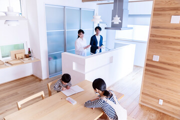 宿題をする姉弟とキッチンで会話をする両親