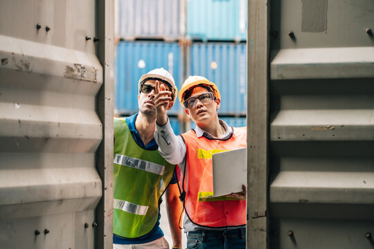 Team Engineer and worker wear safety uniform check control loading freight cargo container use computer laptop at commercial dock warehouse,transportation import,export logistic industrial service