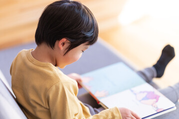 ソファに座って絵本を読む男の子