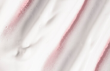 Cosmetic foam of white color on a pink background, facial wash, cream, soap for hygiene. Cosmetic texture macro.