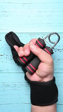 hurt hand doing rehabilitation exercises by squeezing an A shape hand trainer vertical composition