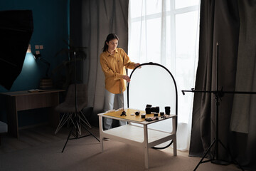 Young female photographer preparing product for a shooting working at home photo studio © Andrii Lysenko