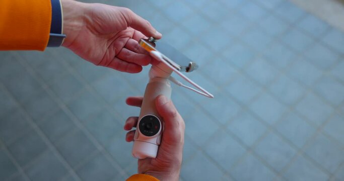 Person connecting a mobile phone to a compact video stabilizer.