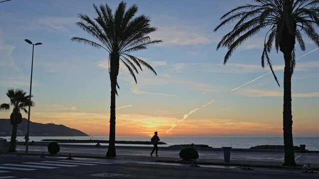 magic of a golden hour sunrise on a beautiful beach road lined with palm trees and people walking alongside