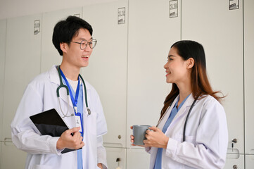 Two cheerful and relaxed young Asian medical students are enjoying talking during the coffee break