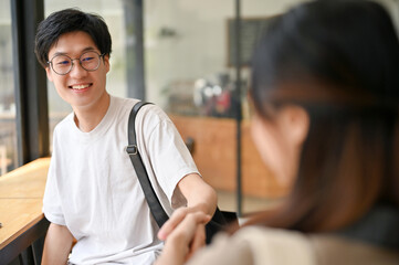 Handsome Asian male college student shaking hand with a female friend.