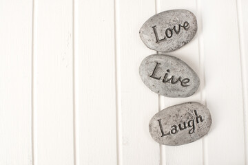 Love, live, Laugh stones on white wooden background