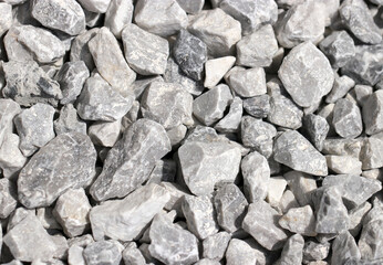 Grayish crushed stone outdoors on a sunny day texture.