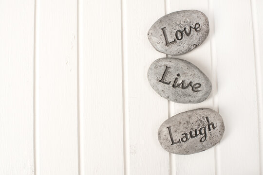 Love, live, Laugh stones on white wooden background