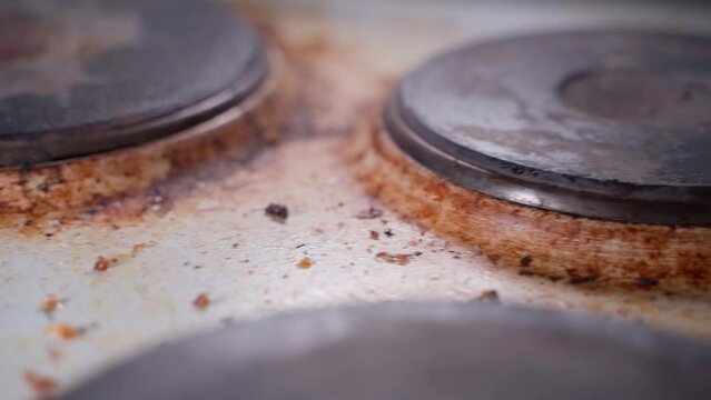 Smooth camera movement over a dirty greasy kitchen electric stove, close-up. Dirty household appliances in a deplorable state
