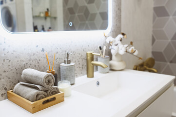 luxury modern bathroom interior with gold tap (faucet), grey stone walls, hand towels and liquid soap. Scandinavian minimalistic style.