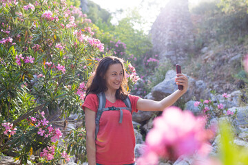 A woman takes a selfie against the background of a landmark, park with oleander flowers