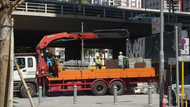 Rising Above: A Dynamic View of Two Men on a Truck Doing Construction Works on Hong Kong's Streets