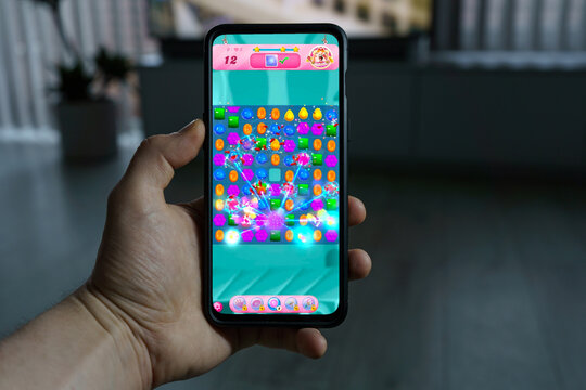 Playing candy crush saga mobile game. Point of view gaming on smartphone
