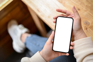 Top view of a woman in casual clothes using her smartphone while relaxing in a cafe.