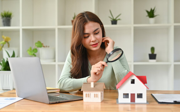 Caucasian female appraiser hold magnifying glass examining house model, checking assessment of dwelling. Concept of real estate appraisal, property, land valuation, house search.