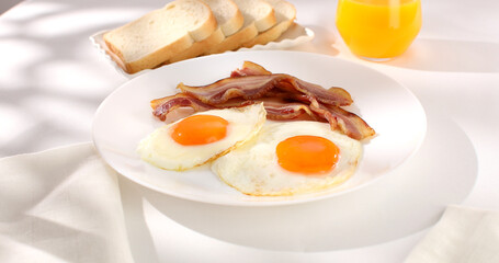 fried eggs with bacon on a plate. breakfast with bread on the table. sunny morning. country style. organic farm food