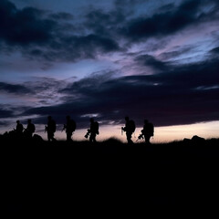 Soldiers walking at dusk silhouette, their forms fading into the darkening blues and purples of the sky. The peaceful serenity of the evening is juxtaposed with the gravity of their situation.
