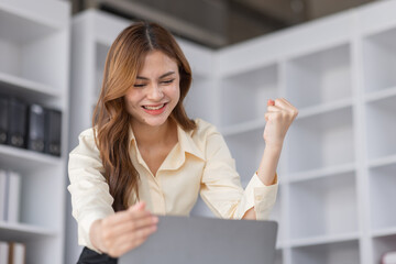 Happy excited successful business asian woman triumphing in office, Portrait of a cheerful Asian businesswoman sitting at the table in office,
