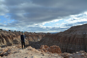 woman in the Cathedral Gorge State Park on a cold day in December, located in a long, narrow valley in southeastern Nevada, where erosion has carved patterns in bentonite clay