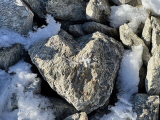 A natural stone heart in the fresh snow of the Swiss mountain massif of the Abula Alps, Zernez - Canton of Grisons, Switzerland (Kanton Graubünden, Schweiz)