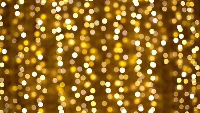 Golden lights garland in bokeh blurred background. Glowing festive golden background.