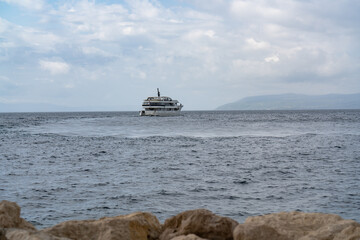 Seascape. A large, tourist liner floats on the waves to the island. Mountains on the horizon. In...