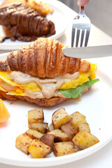 Croissant egg sandwich breakfast with fresh fruit and potatoes. 