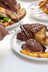 Fototapeta na wymiar Chocolate french toast and banana slice served with chocolate gelato cutting with knife and fork in hand. 