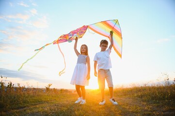 Children launch a kite in the field at sunset