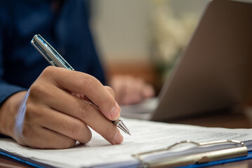 Close up Hand businessman at office desk and signing a contract.