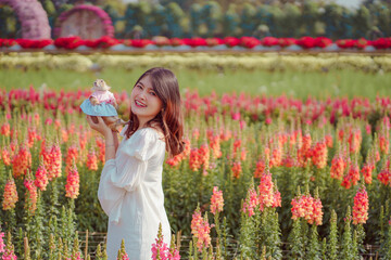 Portrait of young beautiful Asia model woman enjoy with pet prairie dog in spring or summer pink cosmos flower field blooming in garden. girl and animal on sunny.